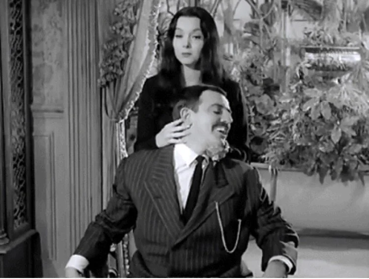 Morticia Addams adjusting Gomez after a stressful day.